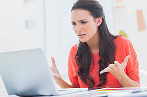 A woman looking at her laptop in frustration