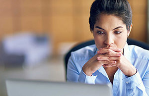 A woman looking at her laptop warily